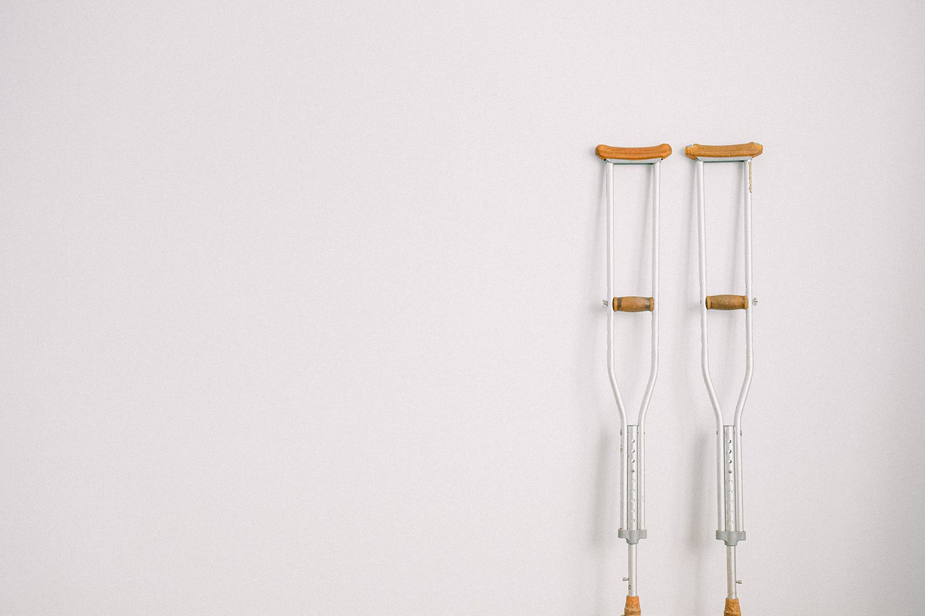 A pair of crutches resting against a pale wall